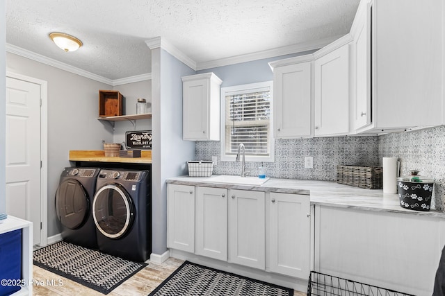 kitchen featuring sink, white cabinetry, ornamental molding, washing machine and clothes dryer, and decorative backsplash