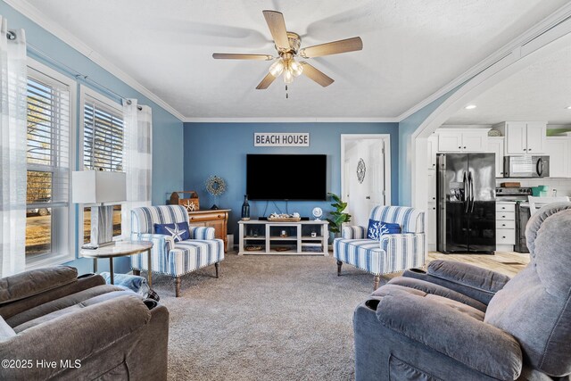 carpeted living room with ornamental molding and ceiling fan