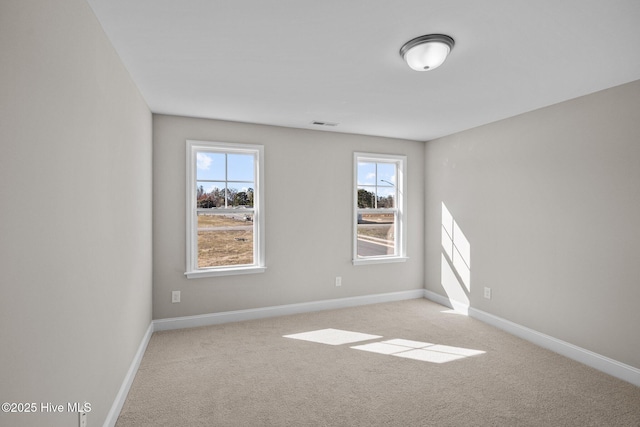 spare room featuring plenty of natural light and light colored carpet