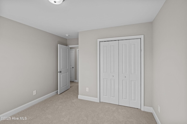 unfurnished bedroom with a closet and light colored carpet