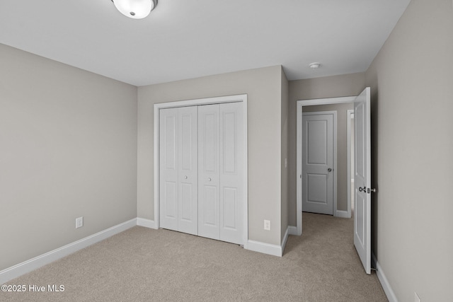 unfurnished bedroom featuring light colored carpet and a closet