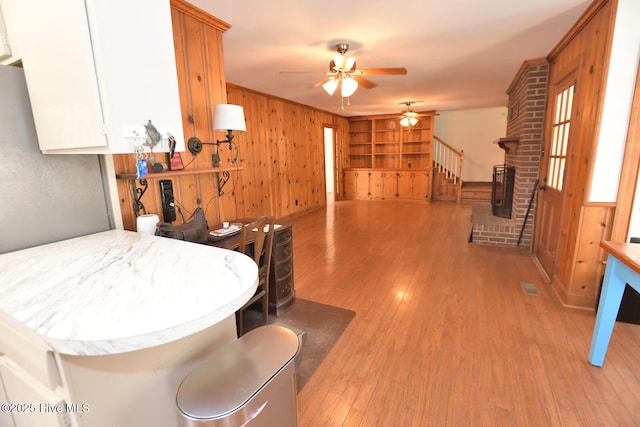 kitchen featuring light hardwood / wood-style floors, a fireplace, white cabinets, built in shelves, and kitchen peninsula