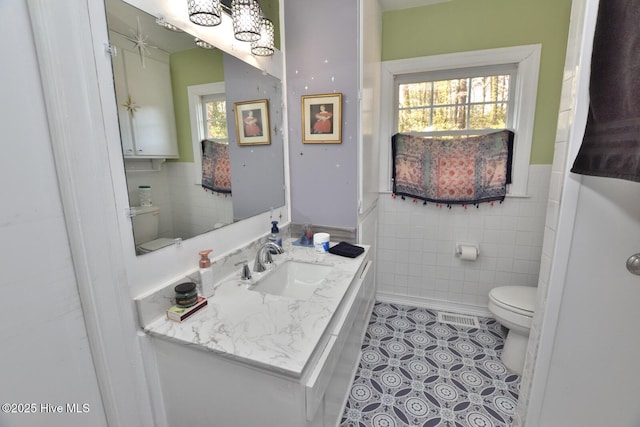 bathroom featuring vanity, toilet, tile patterned floors, and tile walls