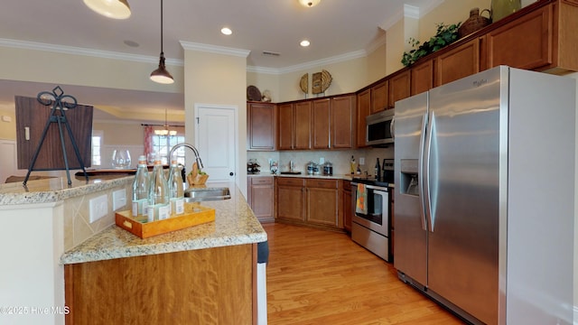 kitchen with light stone countertops, hanging light fixtures, sink, light wood-type flooring, and stainless steel appliances