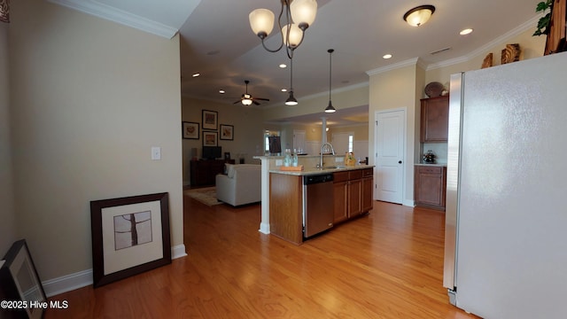 kitchen featuring hanging light fixtures, appliances with stainless steel finishes, sink, light wood-type flooring, and an island with sink