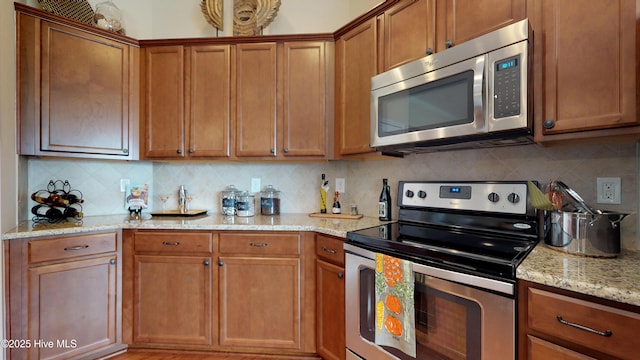 kitchen featuring decorative backsplash, light stone countertops, and appliances with stainless steel finishes