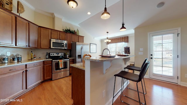 kitchen featuring a kitchen island with sink, a kitchen breakfast bar, pendant lighting, backsplash, and stainless steel appliances