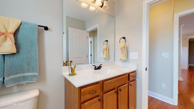 bathroom with hardwood / wood-style flooring, toilet, and vanity