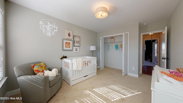 bedroom with a closet, light carpet, and a crib