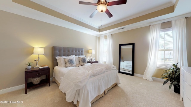 bedroom with crown molding, light colored carpet, a tray ceiling, and ceiling fan