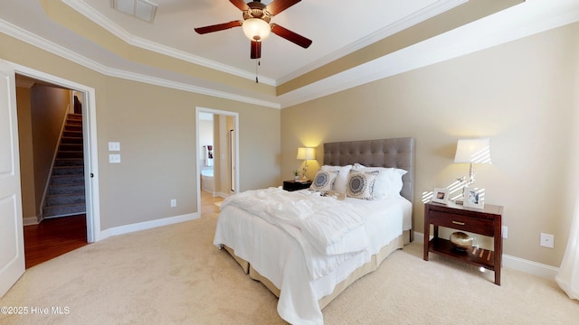 bedroom with ceiling fan, connected bathroom, ornamental molding, and a raised ceiling