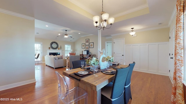 dining room with crown molding, hardwood / wood-style floors, ceiling fan with notable chandelier, and vaulted ceiling