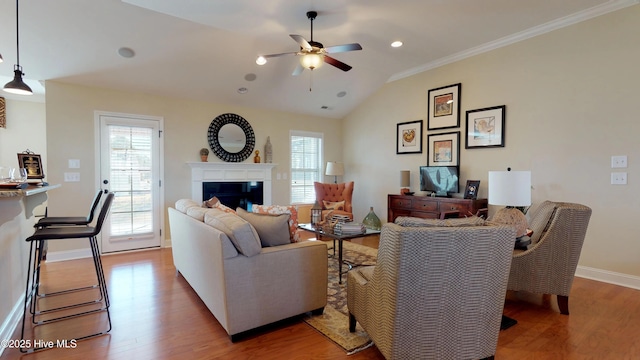 living room with hardwood / wood-style flooring, ceiling fan, ornamental molding, and lofted ceiling