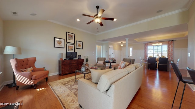 living room with ceiling fan with notable chandelier, hardwood / wood-style floors, and crown molding