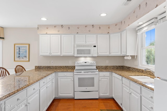 kitchen featuring sink, white appliances, kitchen peninsula, and white cabinets