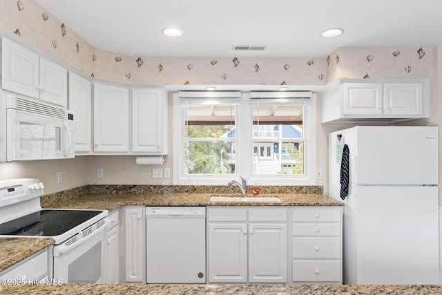 kitchen with dark stone countertops, sink, white appliances, and white cabinets