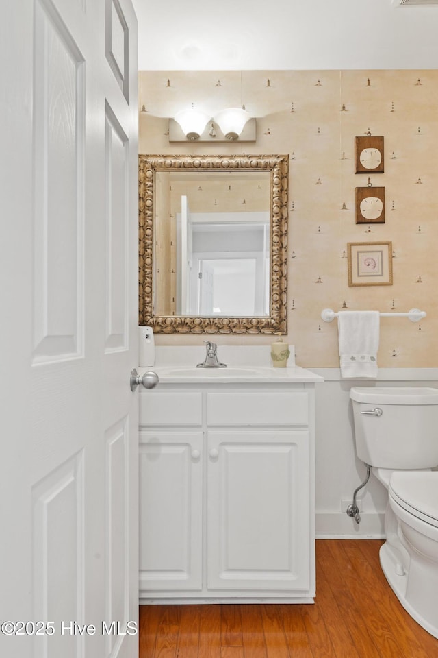 bathroom with wood-type flooring, vanity, and toilet