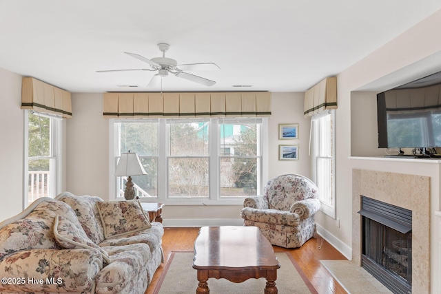 living room featuring ceiling fan, a fireplace, and light hardwood / wood-style floors