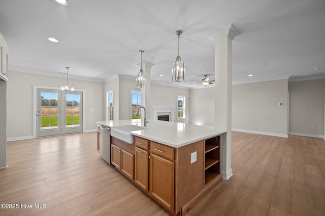 kitchen with dishwasher, light hardwood / wood-style flooring, sink, hanging light fixtures, and a center island with sink