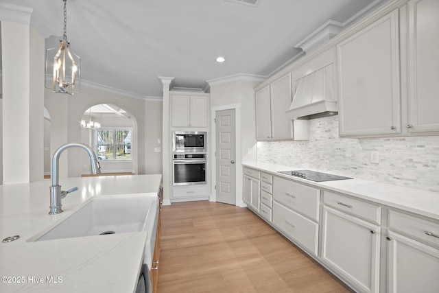 kitchen featuring light stone countertops, white cabinetry, stainless steel appliances, sink, and a notable chandelier