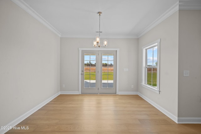 unfurnished dining area featuring crown molding, plenty of natural light, light wood-type flooring, and a notable chandelier