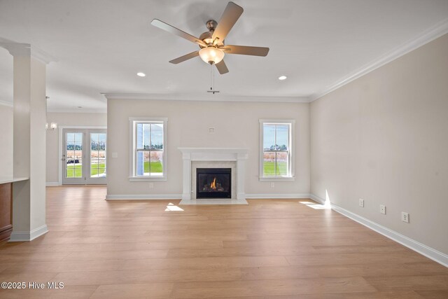 unfurnished living room featuring ceiling fan, ornamental molding, light hardwood / wood-style floors, and a fireplace