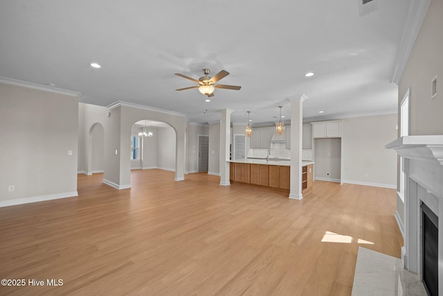 unfurnished living room with ceiling fan, crown molding, and light hardwood / wood-style floors