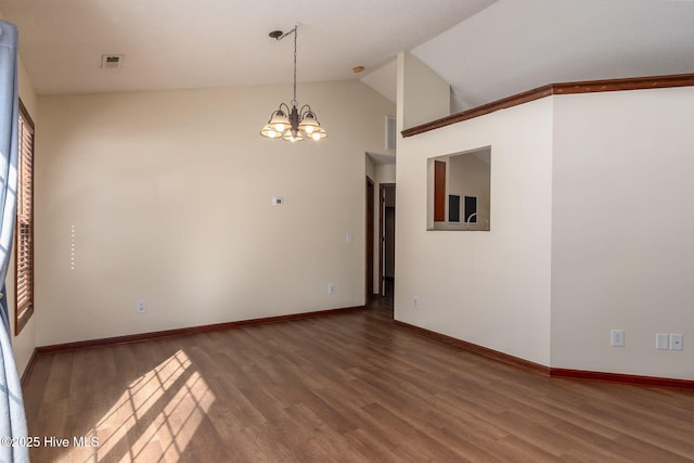 spare room with lofted ceiling, a notable chandelier, and wood-type flooring