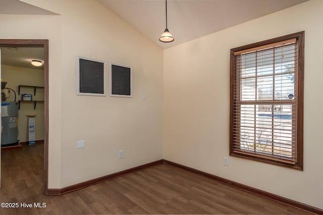 spare room with lofted ceiling, electric water heater, and dark wood-type flooring