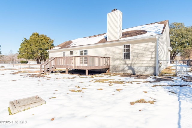 snow covered back of property featuring a wooden deck