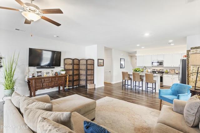 living room featuring dark wood-type flooring and ceiling fan