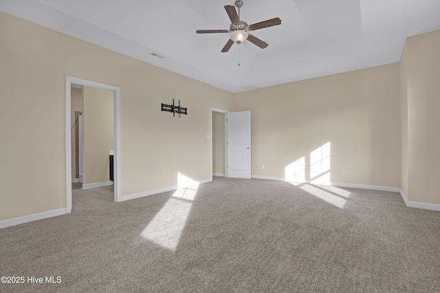 carpeted spare room with ceiling fan and a tray ceiling