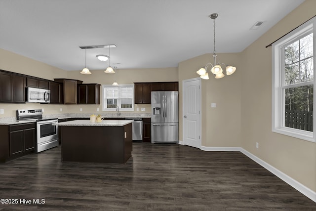 kitchen featuring hanging light fixtures, dark brown cabinets, stainless steel appliances, and a kitchen island