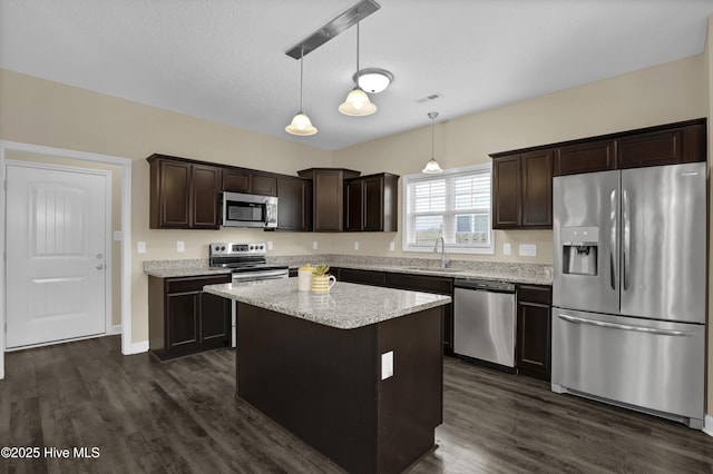 kitchen with a kitchen island, appliances with stainless steel finishes, decorative light fixtures, sink, and dark brown cabinets