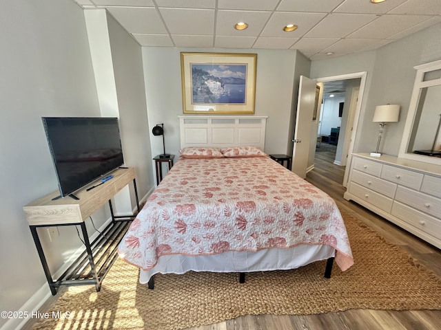 bedroom featuring a drop ceiling and hardwood / wood-style flooring