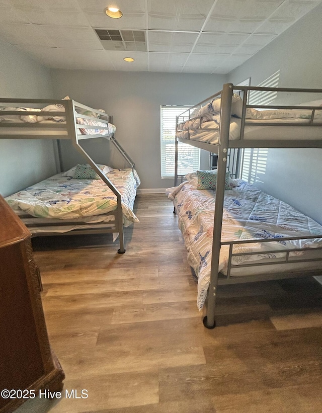 bedroom with hardwood / wood-style floors and a paneled ceiling