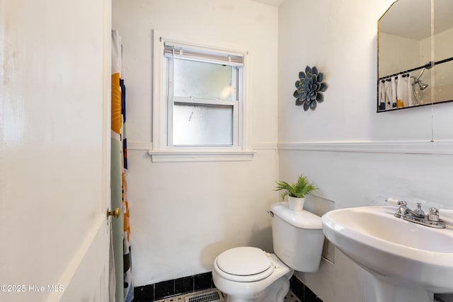 bathroom featuring a shower with shower curtain, toilet, and sink