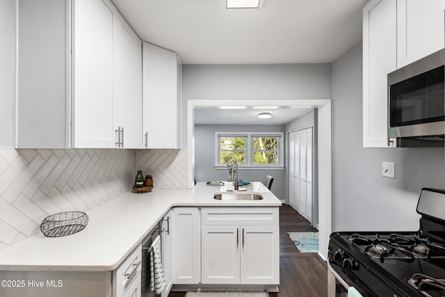 kitchen with sink, backsplash, white cabinets, dark hardwood / wood-style flooring, and stainless steel appliances