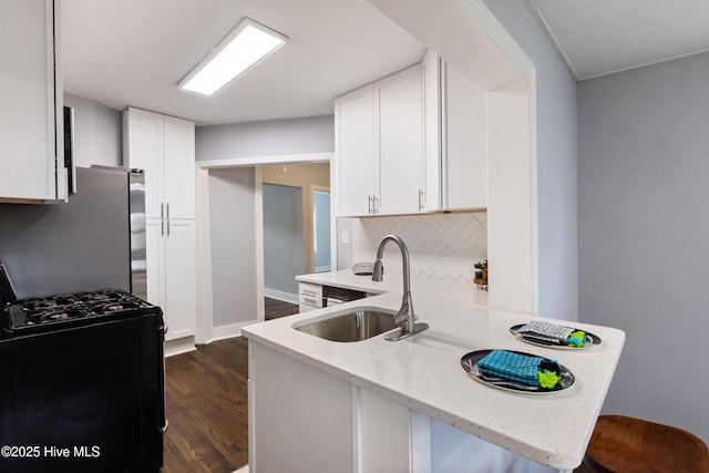 kitchen with black range with gas cooktop, kitchen peninsula, sink, and white cabinets