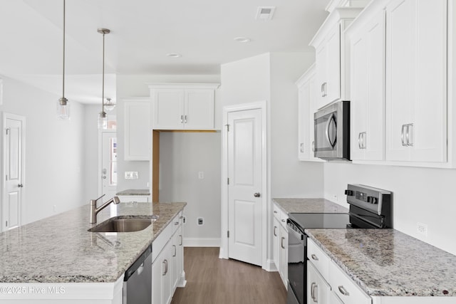 kitchen featuring white cabinetry, decorative light fixtures, stainless steel appliances, and an island with sink