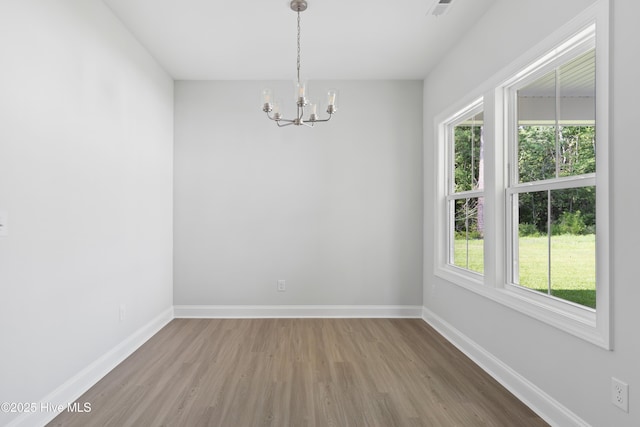 empty room featuring an inviting chandelier and hardwood / wood-style flooring