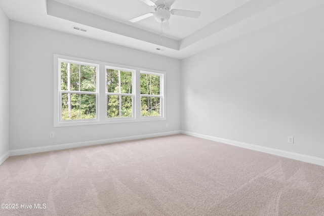 carpeted empty room featuring a raised ceiling and ceiling fan