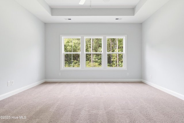 carpeted empty room featuring ceiling fan and a tray ceiling