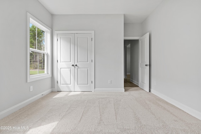 unfurnished bedroom featuring light colored carpet and a closet