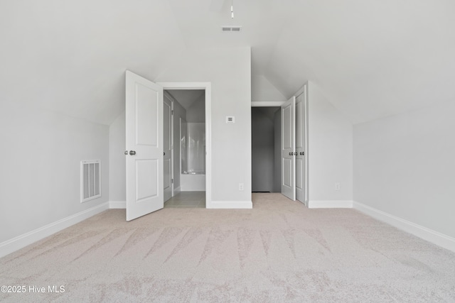 unfurnished bedroom with light carpet and lofted ceiling