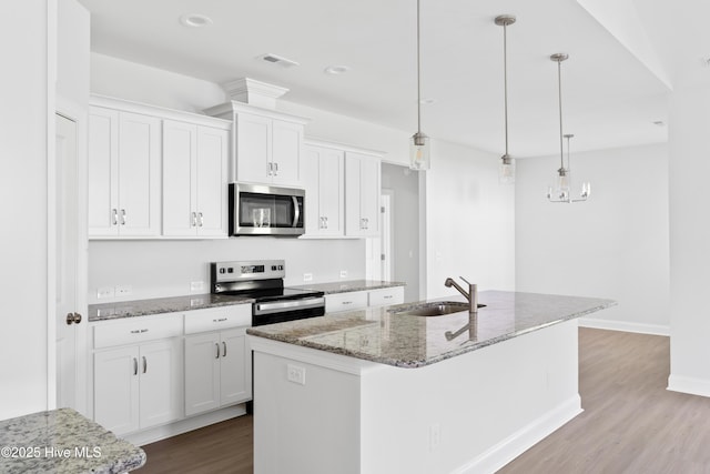 kitchen featuring stainless steel appliances, white cabinetry, sink, and an island with sink