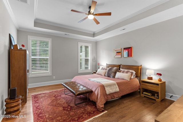 bedroom with crown molding, ceiling fan, a raised ceiling, and hardwood / wood-style flooring