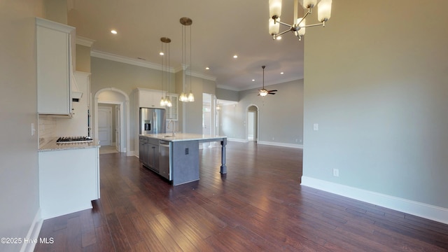 kitchen featuring appliances with stainless steel finishes, decorative light fixtures, white cabinetry, sink, and a center island with sink