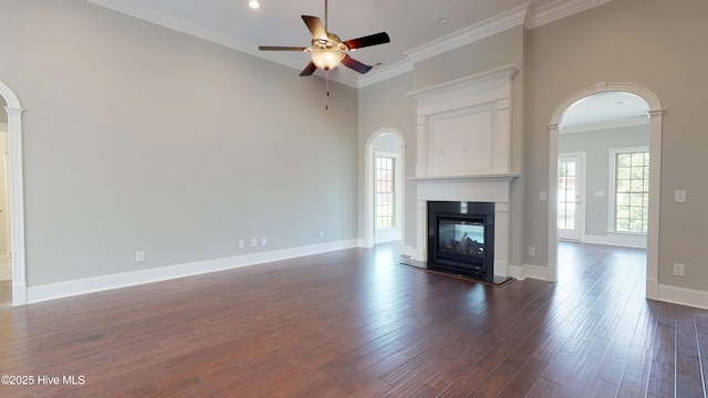 unfurnished living room with a ceiling fan, dark wood finished floors, arched walkways, a multi sided fireplace, and ornamental molding