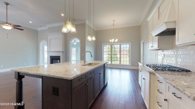 kitchen featuring pendant lighting, appliances with stainless steel finishes, white cabinetry, an island with sink, and sink